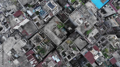 Empty old houses at urban slum area, prepared for demolition, top-down aerial shot. Old district of city will be cleared for new modern development.  Camera fly down, show roofs of packed houses photo
