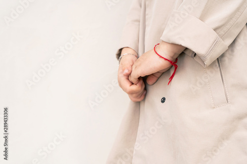 Children's hands close-up. A red thread is put on a child’s hand for good luck. Girl holds hand in hand