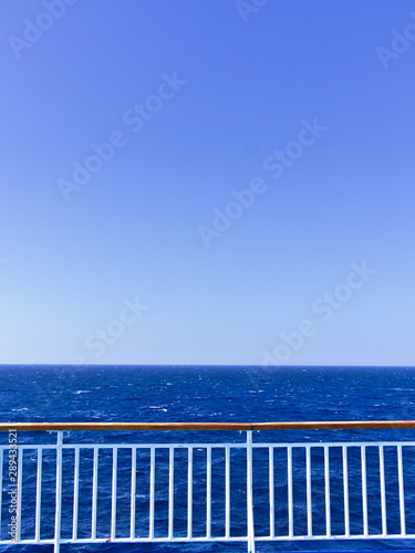 Ship deck railing  while sailing on open sea. Vivid blue color with copy space.