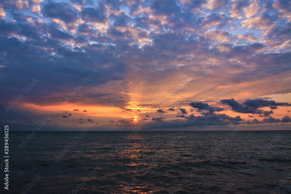 a sunrise with clouds on the sea beach