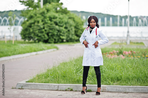 Young african american female doctor in white coat with a stethoscope posed outdoor. © AS Photo Family
