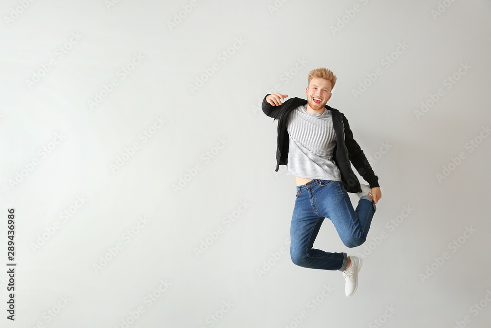 Handsome jumping young man against light background