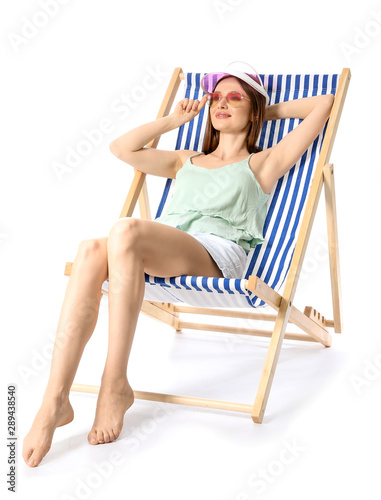 Beautiful young woman relaxing on sun lounger against white background