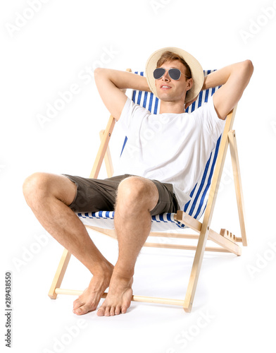Fotografie, Obraz Young man relaxing on sun lounger against white background