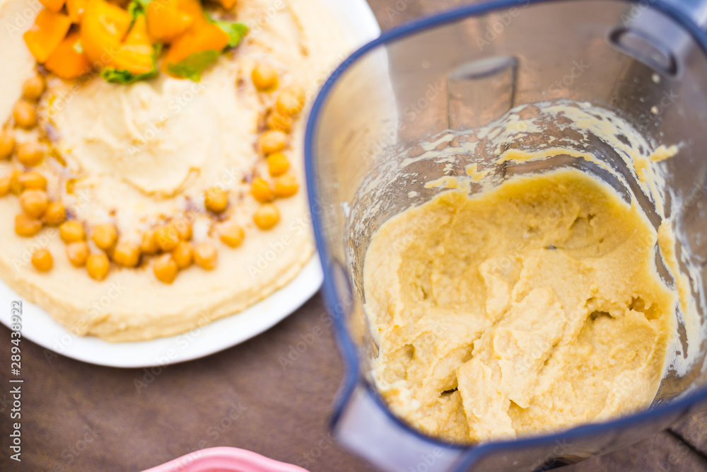 Original homemade arabic chickpea hummus with olive oil and cumin. Creamy dip paste. Blender or food processor with made hummus paste.