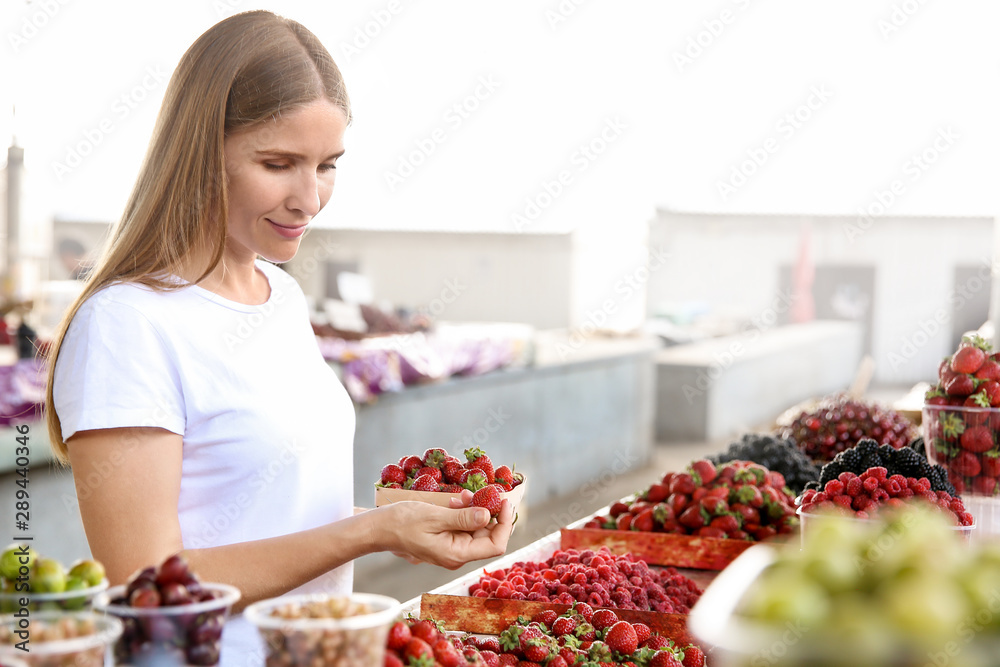 Woman with fresh strawberries on counter at market Woman with fresh strawberries on counter at market