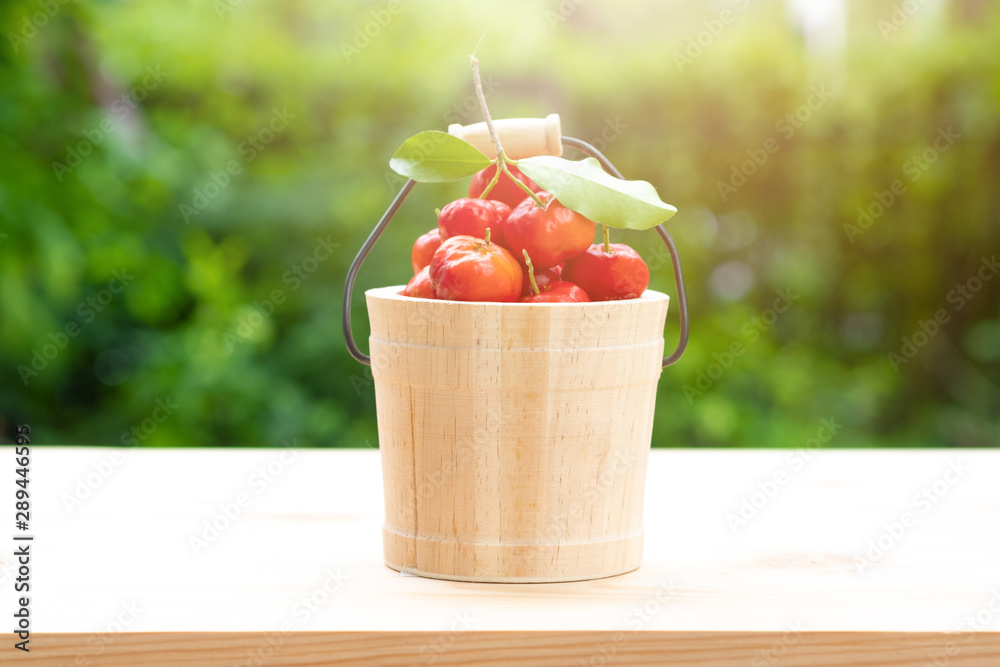 Acerola cherry in wooden bucket on wooden background. Select  focus, Barbados cherry, Malpighia emarginata, high vitamin . Acerola fruit.