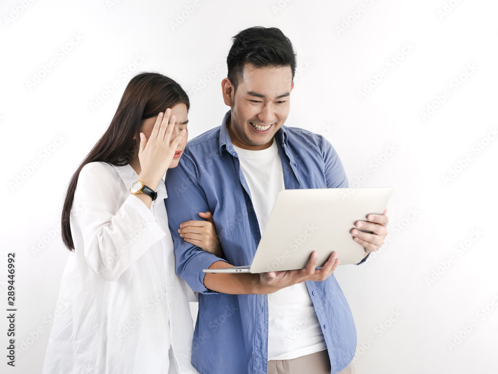 Happy Asian couple using laptop against white wall, lifestyle concept. Happy Asian couple using laptop against white wall, lifestyle concept.