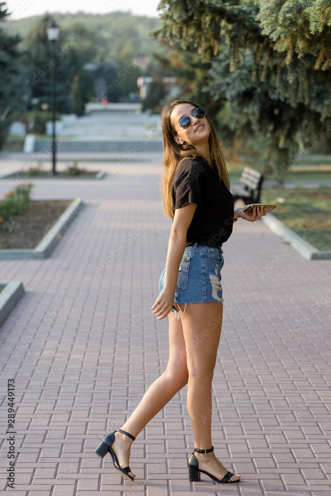 A young girl sits on a bench in a park and makes notes. Dressed in a free style. Business woman talking on the phone with customers.	