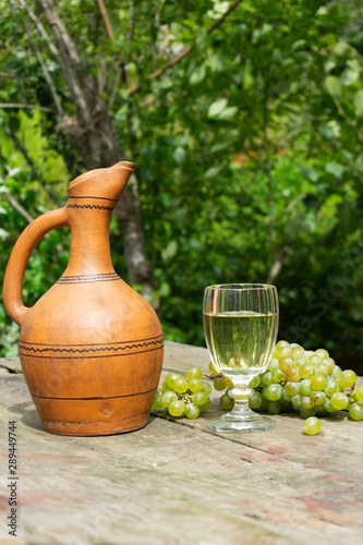 Homemade wine of Georgia. A glass of white homemade wine  grapes and a clay decanter. Bio wine concept.