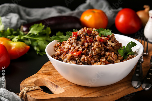 Healthy buckwheat cooked with vegetables in a white bowl on a dark background, a dish of Azerbaijani cuisine, horizontal orientation