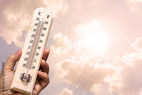 Hand hoding the thermometer with sunny sky.High temperamture concept.