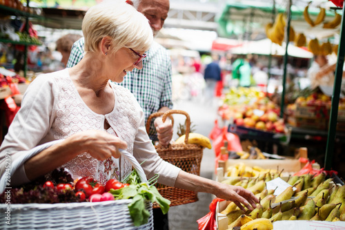 Obraz na plátne Mature woman buying vegetables at farmers market