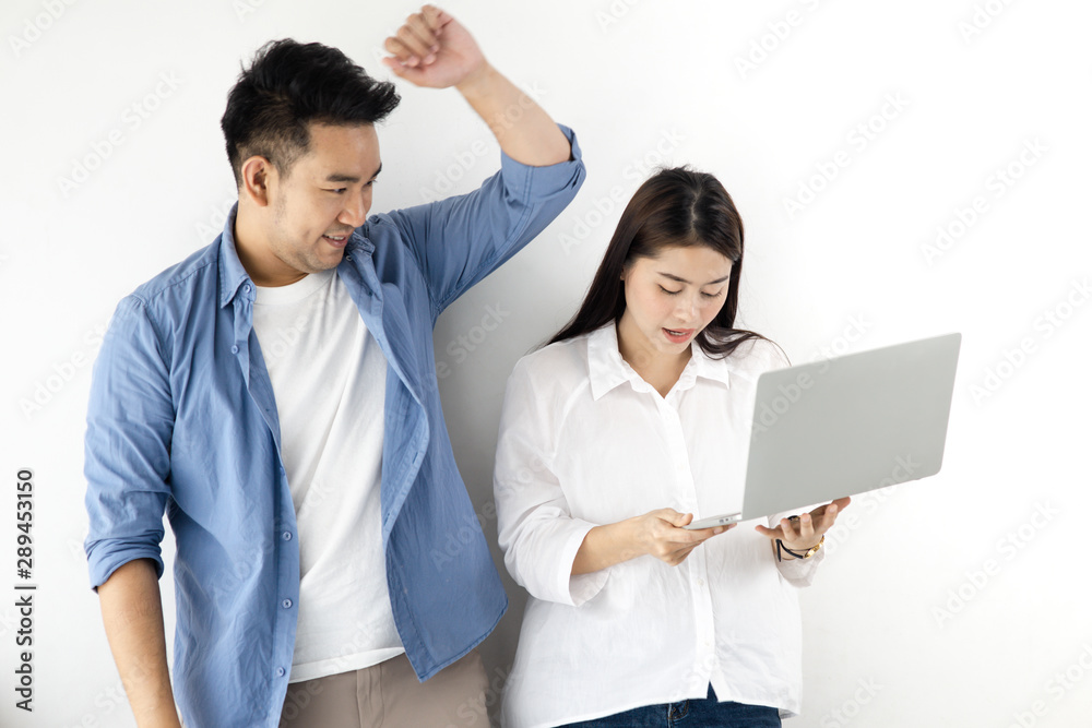 Happy Asian couple using laptop against white wall, lifestyle concept. Happy Asian couple using laptop against white wall, lifestyle concept.