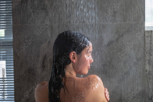Young brunette woman taking a shower in a modern bathroom