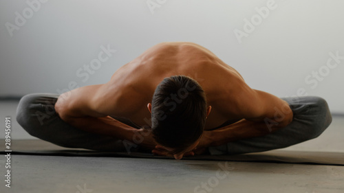 Beautiful sporty fit man practices yoga asana Baddha konasana - bound angle pose photo