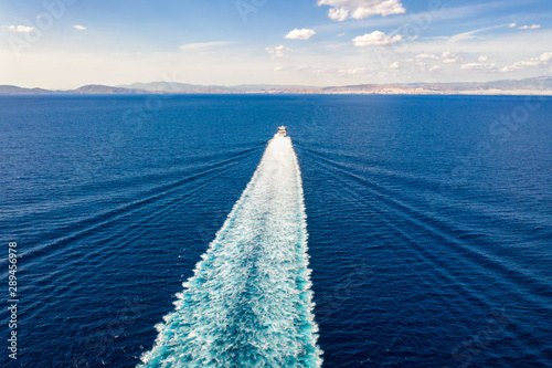Luftaufnahme einer Jet Passagierfähre in voller Fahrt über blauem Meer welches eine Spur aus Luftblasen und Wellen hinterlässt