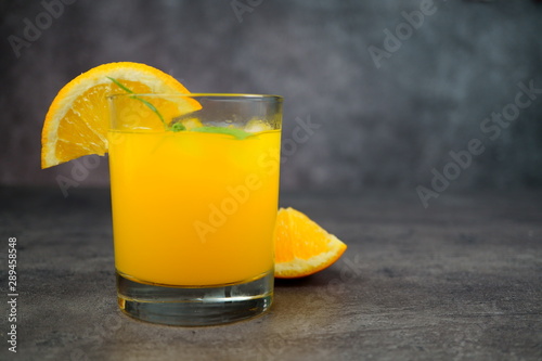 A glass of fresh orange juice on grey background.
