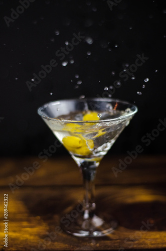 Martini glass with olive splash on dark background
