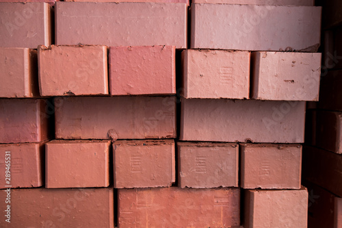 Pile of stacked new red bricks. Clay brick blocks ready for construction.