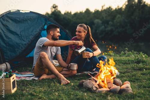 happy couple enjoying evening camping by the camping fire