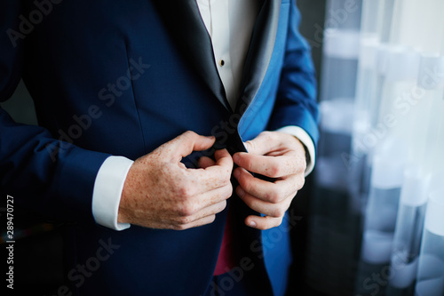 the groom straightens the wedding suit