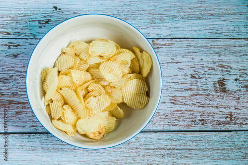 Potato chip in the white bowlon the wood grunge blue paint color, Potato fried snack on wood table  photo