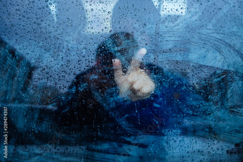 window dripping drops during the rain, a man stands behind the glass © sipcrew