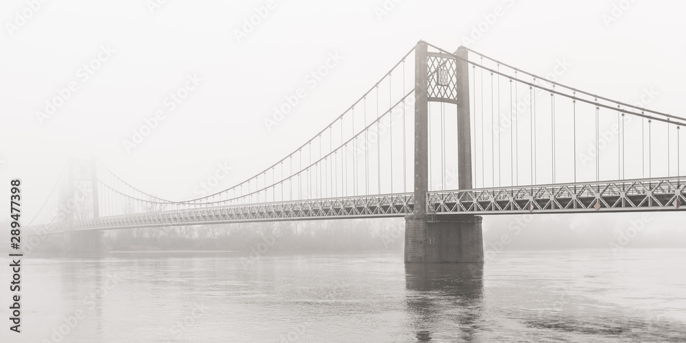 Suspension bridge over the Loire disappears on a foggy day, Ancenis, France