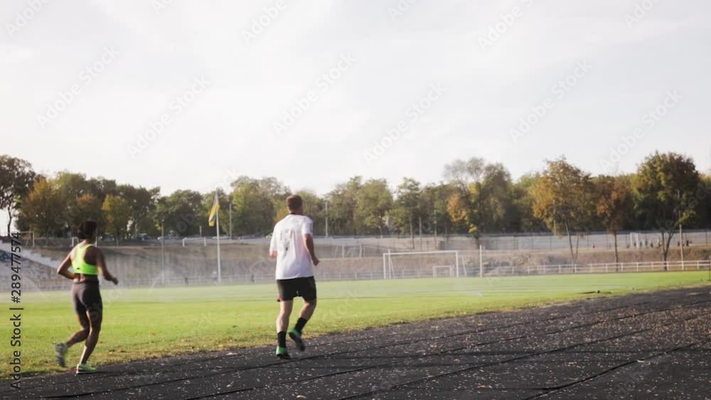 Sports people run and train in the stadium along the treadmills against the green grass of the stadium, which is grown and watered. Sports people run and train in the stadium along the treadmills against the green grass of the stadium, which is grown and watered.