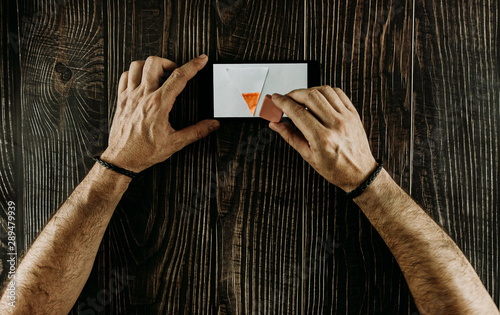 Male hands erasing on mobile by marker on wood background. Top view. Copy space