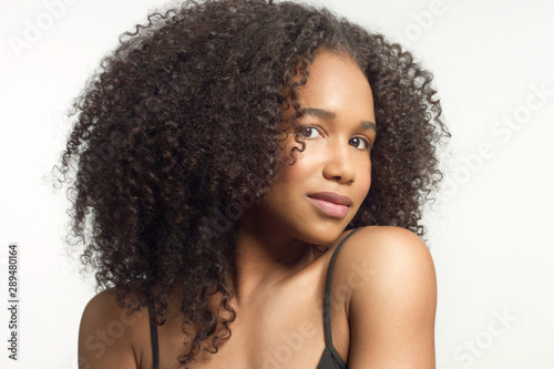 closeup portrait of young mixed race model with curly hair in studio with natural neutral makeup with big afro hair on white