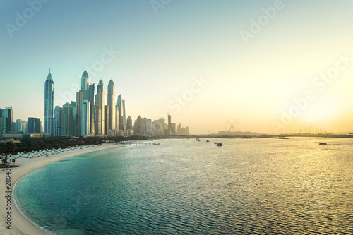 Dubai Marina at sunset. Panorama view of skyscraper buildings, beach, clear sky and sea at dawn. Scenic luxury city skyline in United Arab Emirates, UAE. Panoramic cityscape and landscape.