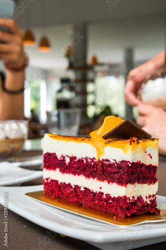 a piece of cheese cake red valvet with orange jam on top photo
