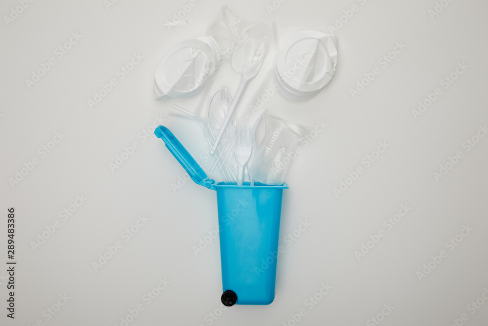 top view of blue recycle bin with crumpled plastic cups, forks and spoons on white background with copy space top view of blue recycle bin with crumpled plastic cups, forks and spoons on white background with copy space