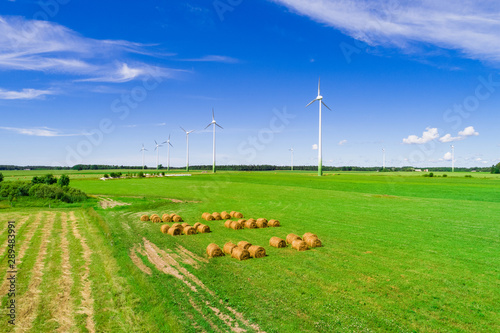 Wind turbines in open green field with blue sky background. 
