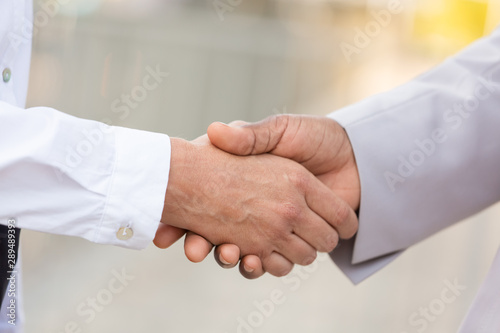 Closeup of business professionals handshake. Business man and woman shaking hands outside. Partnership concept