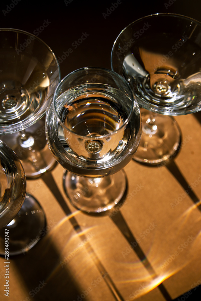 Drink glasses with strong and bright shadows on brown background. Modern art food and water concept 