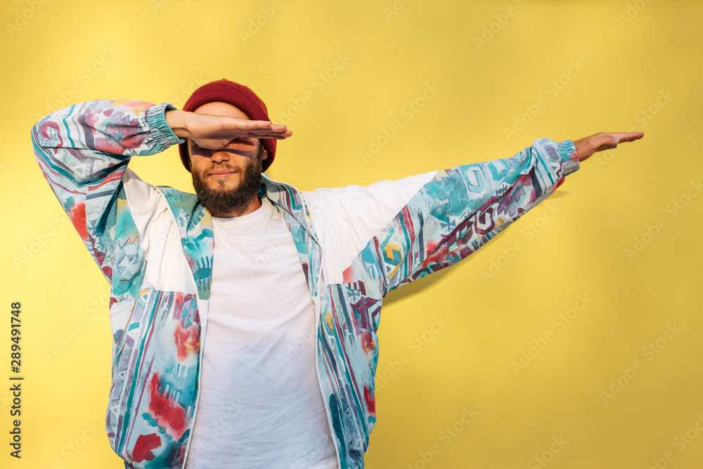 Stylish young hipster man with beard in red hat and a retro jacket of 90s on yellow background.Crazy hipster guy emotions. Collage in magazine style  - obrazy, fototapety, plakaty 