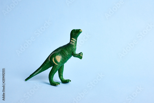 Tyrannosaur green toy. Isolated on blue background. Copy space