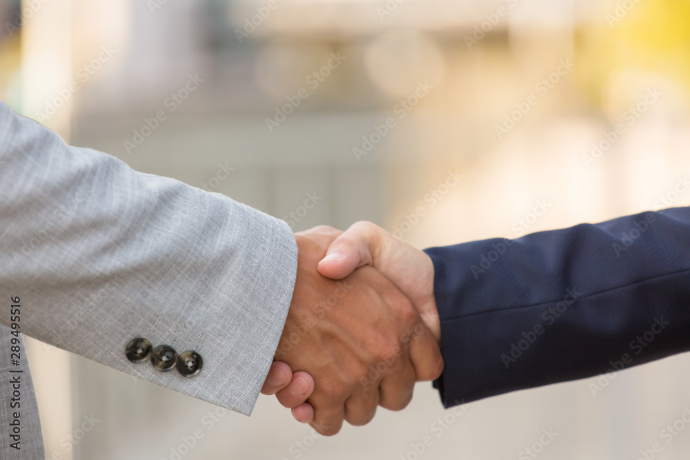 Fototapeta premium Closeup of business partners handshake. Business man and woman shaking hands with each other outside. Closing deal concept