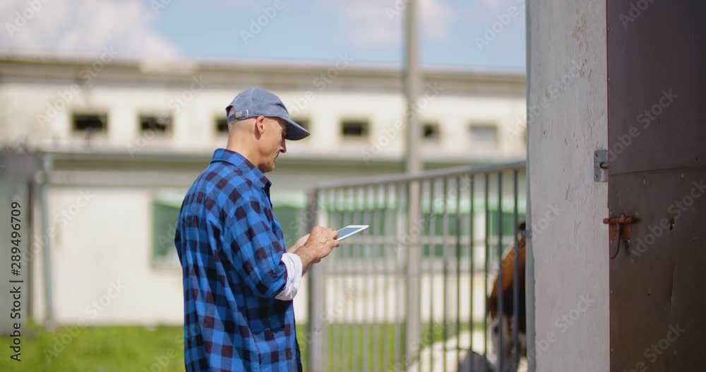 Farmer gesturing while writing on clipboard against barn Farmer gesturing while writing on clipboard against barn