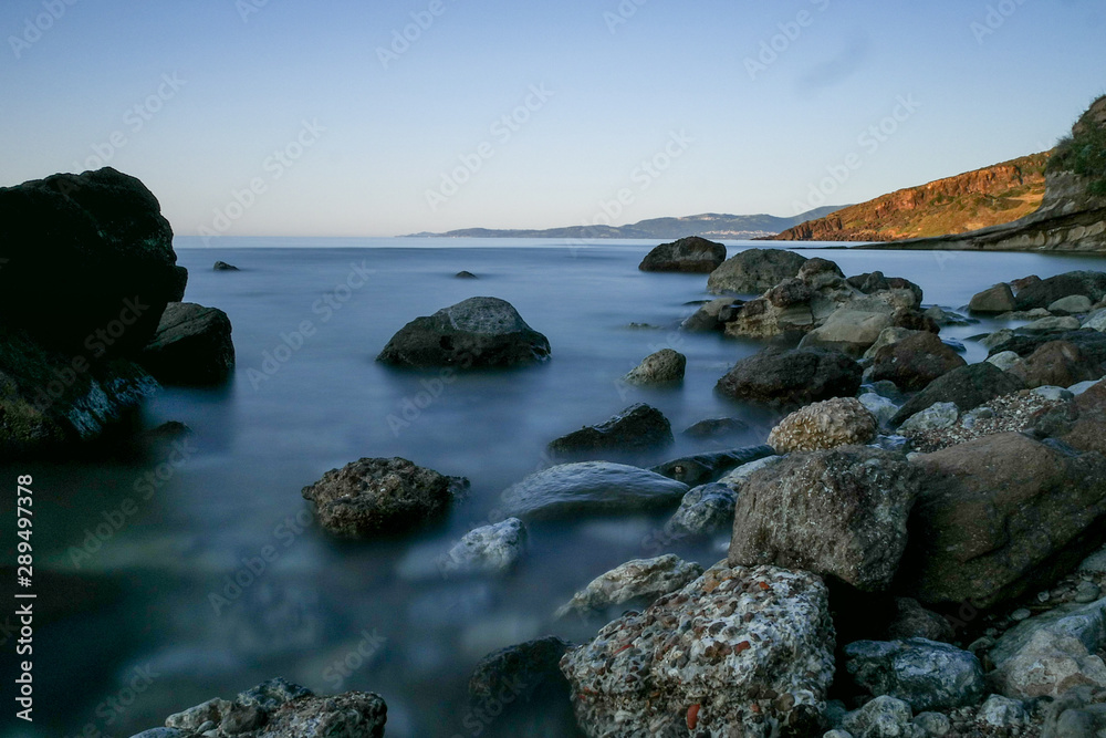 Long exposure image of Dramatic sky seascape with rock in sunset scenery background Long exposure image of Dramatic sky seascape with rock in sunset scenery background