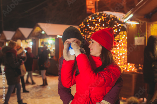 Portrait of woman giving drink to her partner at Christmas fair