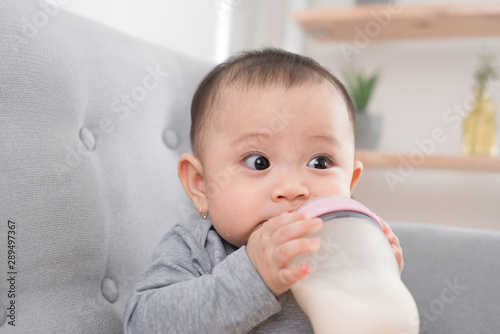 Asian baby infant eating milk from bottle, 9 months after birth