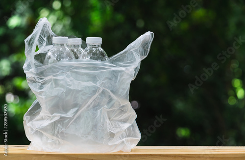 Plastic bottle in plastic bag on wooden in nature background. global warming concept.