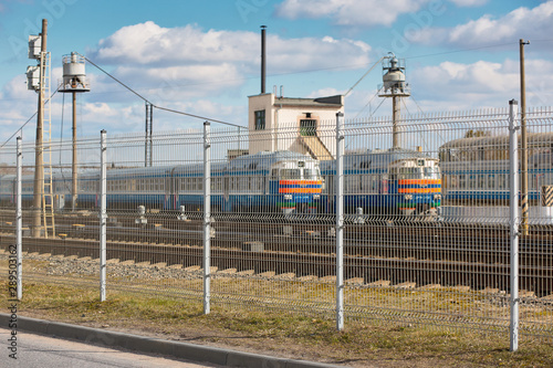 Wire fence restricting access to train depot with standing trains out of focus railway depot background. Concept of protecting strategic objects from unauthorized access