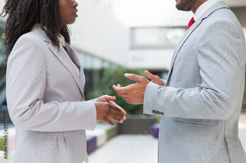 Two business colleagues discussing work issues. Closeup of business man and woman standing in hallway, talking and gesturing. Business communication concept