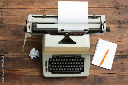 Vintage typewriter with the Cyrillic alphabet and a sheet of paper on an old table, a notebook on a spring and a pen