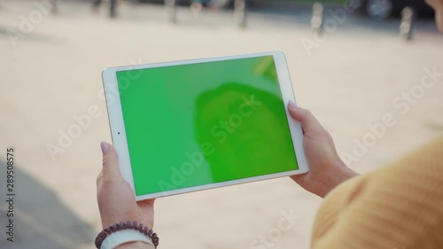 Close up hands woman using tablet device computer with green screen outdoors in street at sunlight horizontal bloom message pad technology chroma key female digital girl app chat finger slow motion